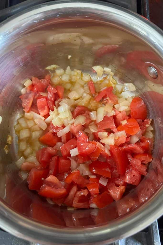 Onions and tomatoes in a pan on the stove.