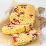 A slice of cranberry bread on a cutting board.