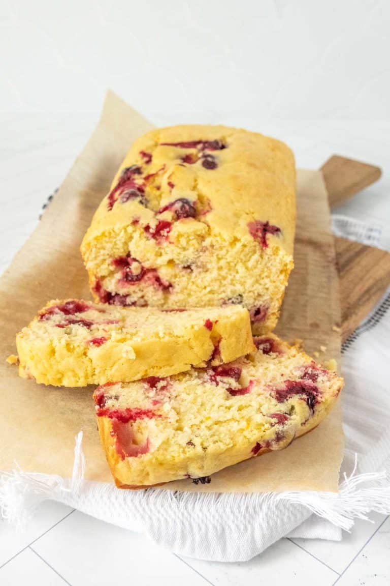 A slice of cranberry bread on a cutting board.