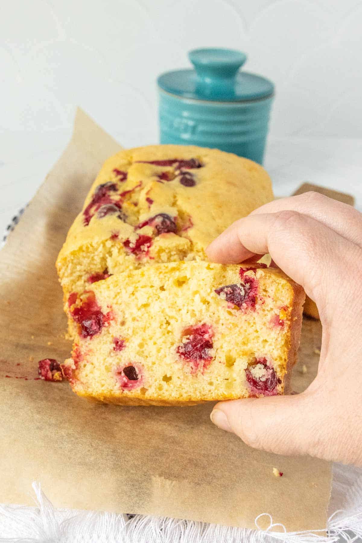 A slice of cranberry bread on a piece of parchment paper.