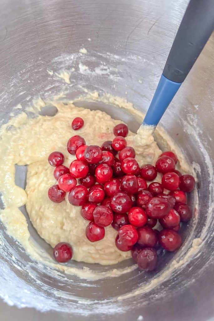 Cranberries are being mixed into a bowl of batter.