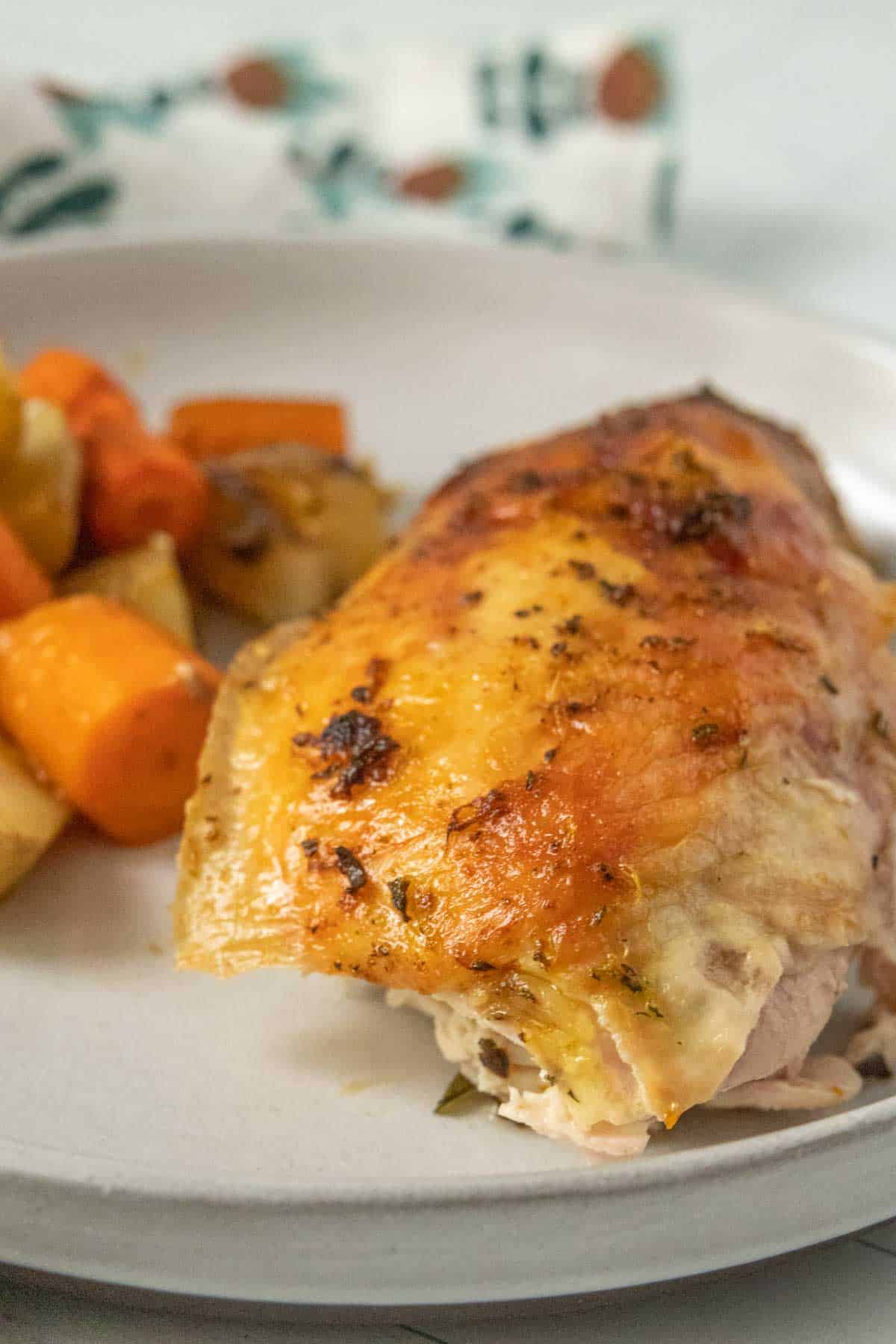 A plate of roasted chicken with carrots and potatoes.