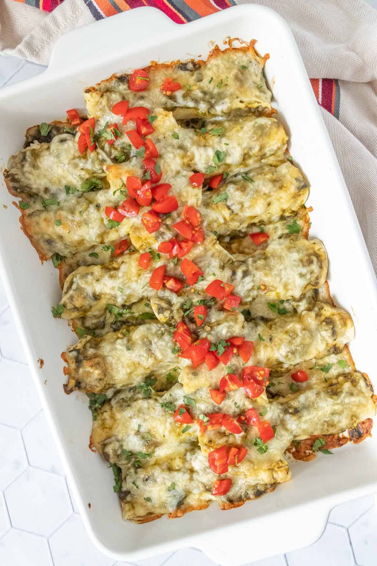 Cheesy enchiladas in a white baking dish.