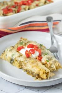 Mexican enchiladas on a plate with sour cream.