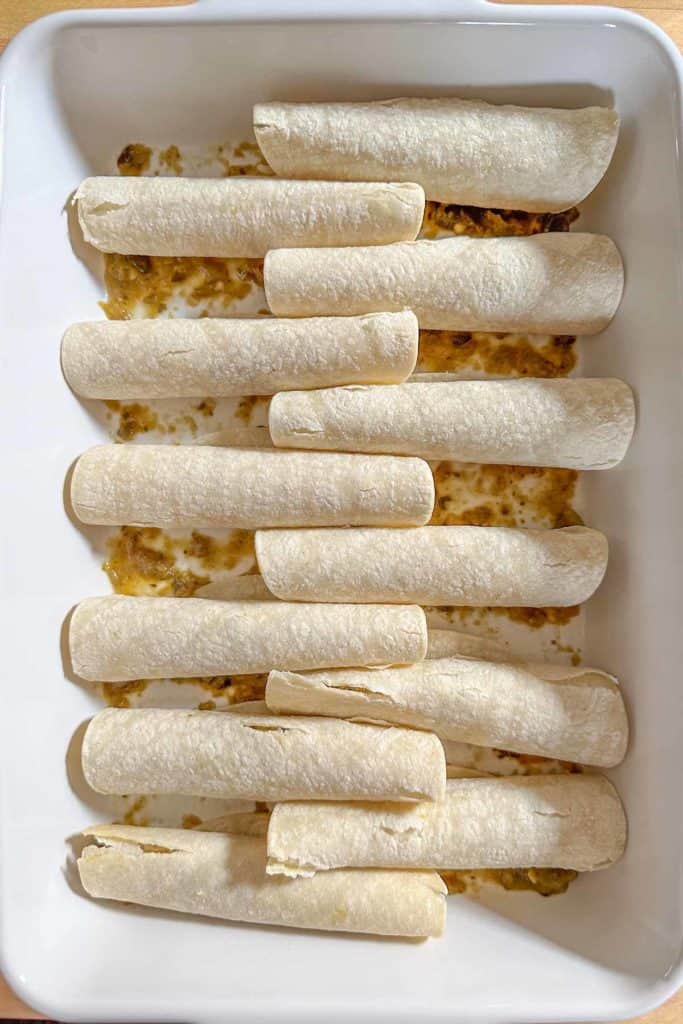 Enchiladas in a baking dish on a wooden table.