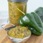 A jar of green chile sauce on a cutting board.