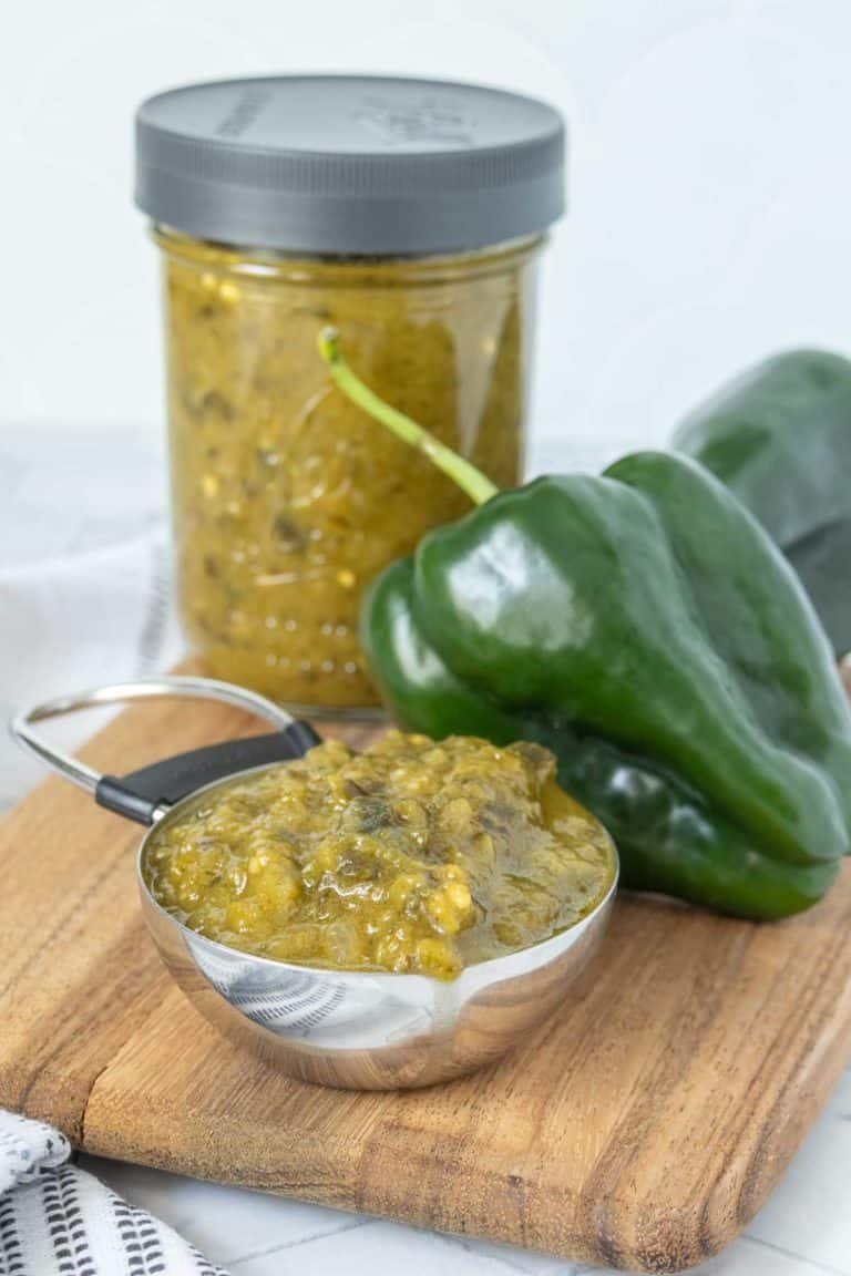 A jar of green chile sauce on a cutting board.