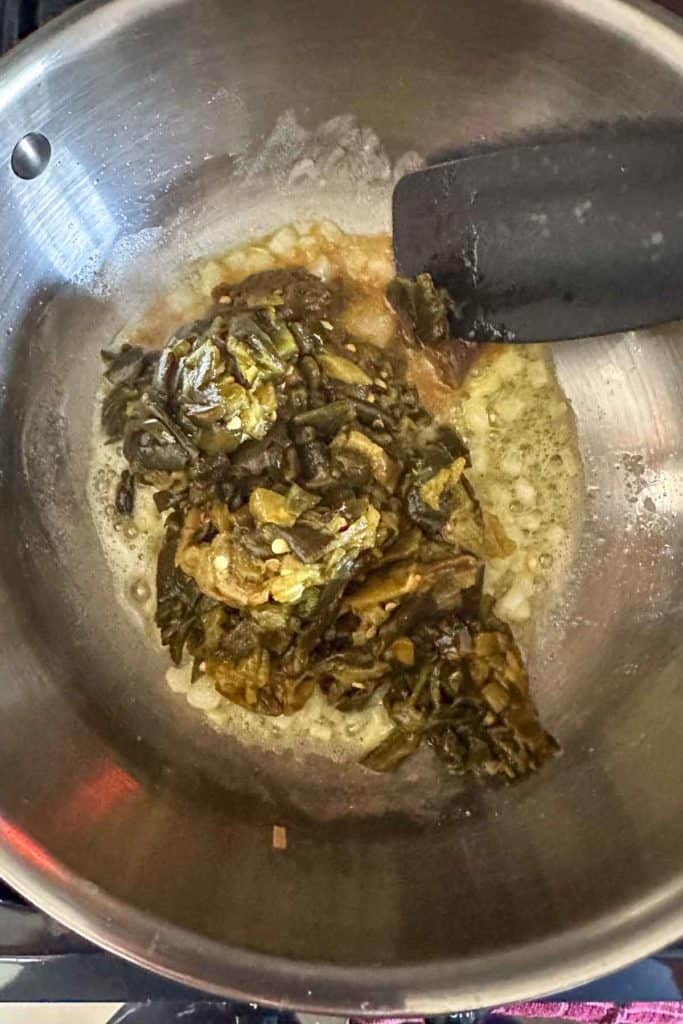 Sauteing green chiles in a pan with a spatula.