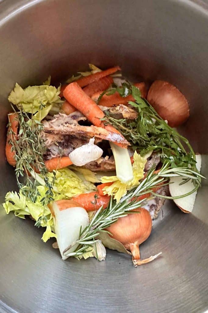 A pot filled with carrots, onions, and other vegetables.