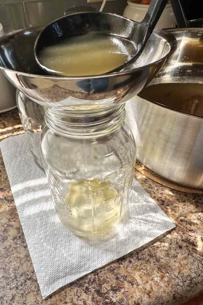 Broth being poured into a jar.