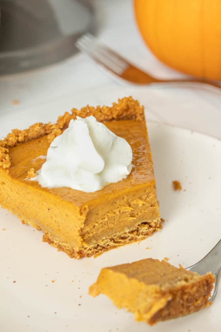 A slice of pumpkin pie on a plate with whipped cream.