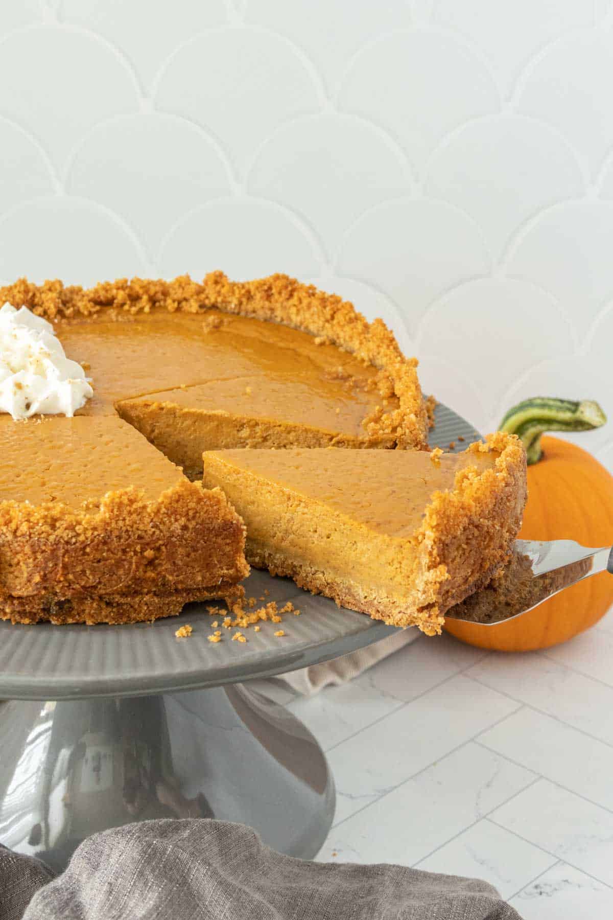 Pumpkin pie on a plate with a slice taken out.