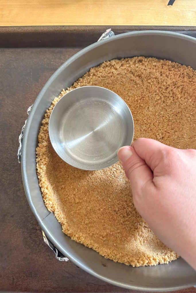 A person pressing crust into a pan.