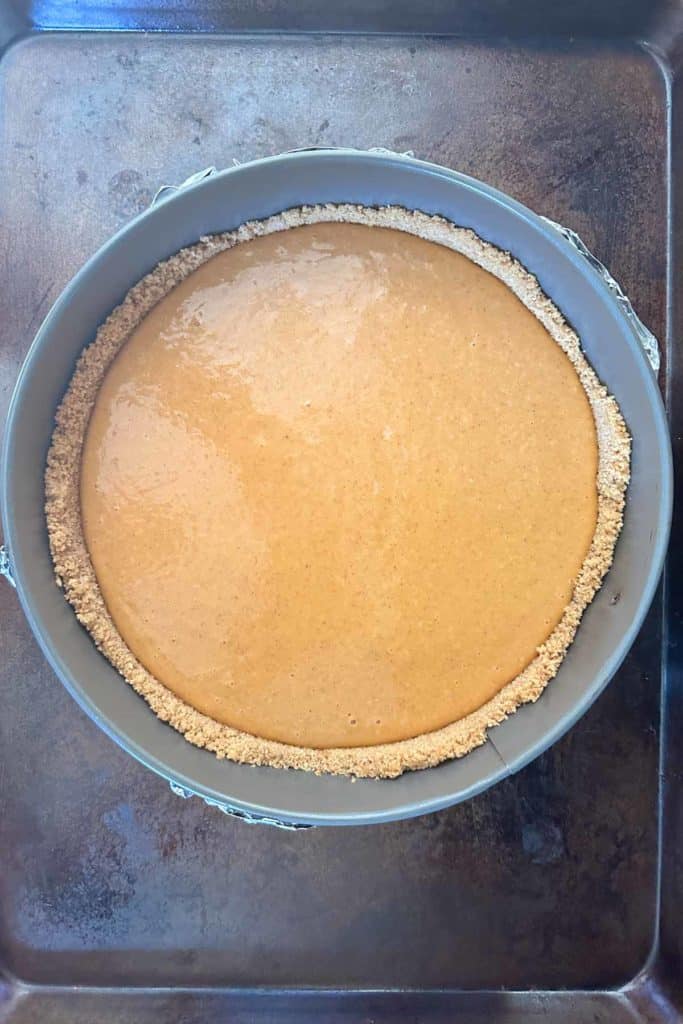 A pumpkin pie in a pan on a baking sheet.