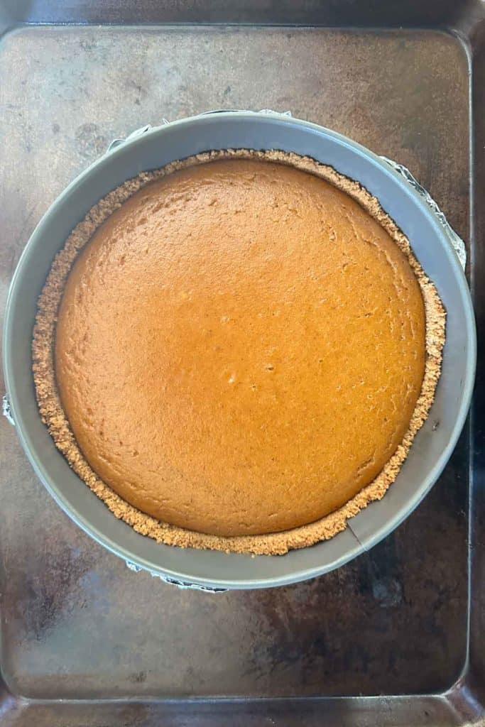 A pumpkin pie in a pan on a baking sheet.