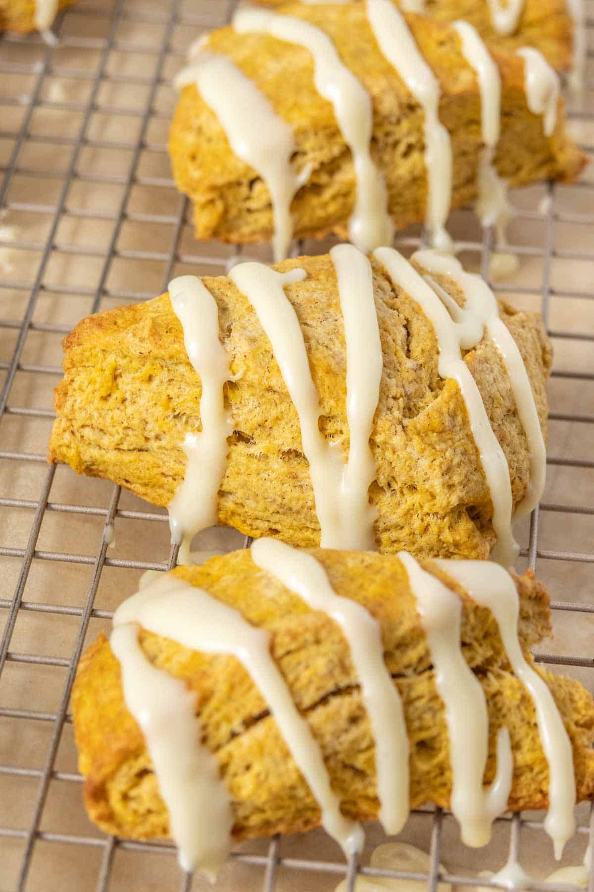 Pumpkin scones with icing on a cooling rack.