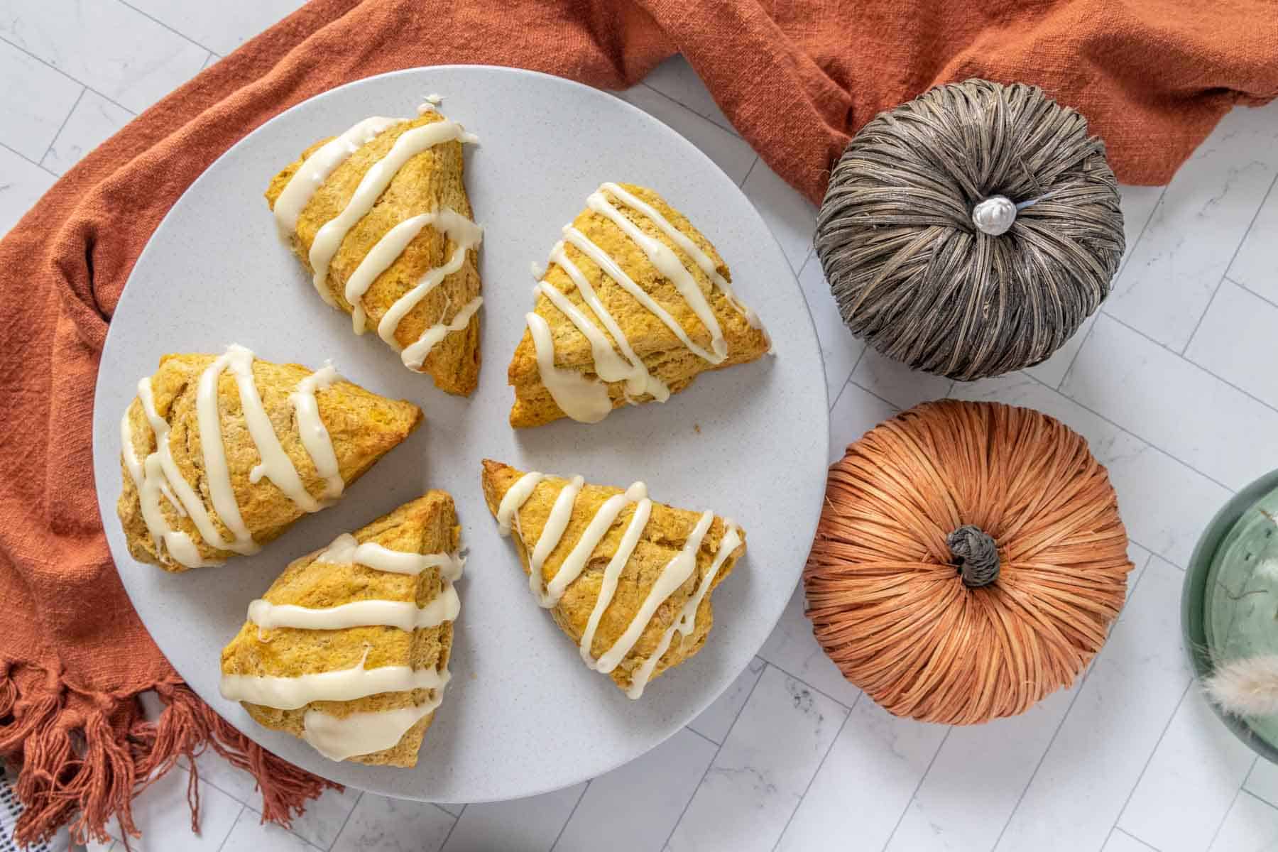 Pumpkin scones on a plate with pumpkins.