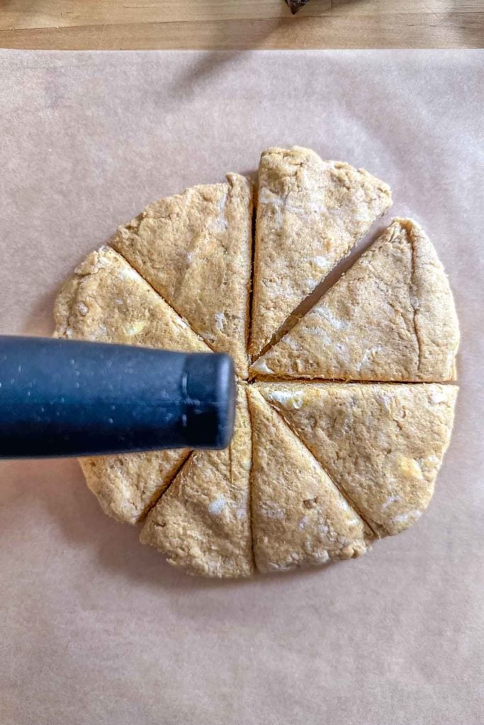 A slice of a scone being cut with a knife.