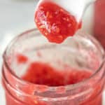 Raspberry jam in a jar with a spoon.