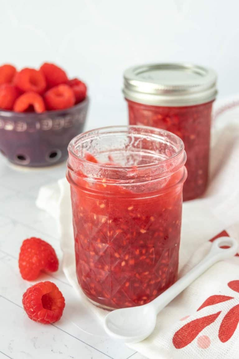 Raspberry jam in a jar with a spoon.