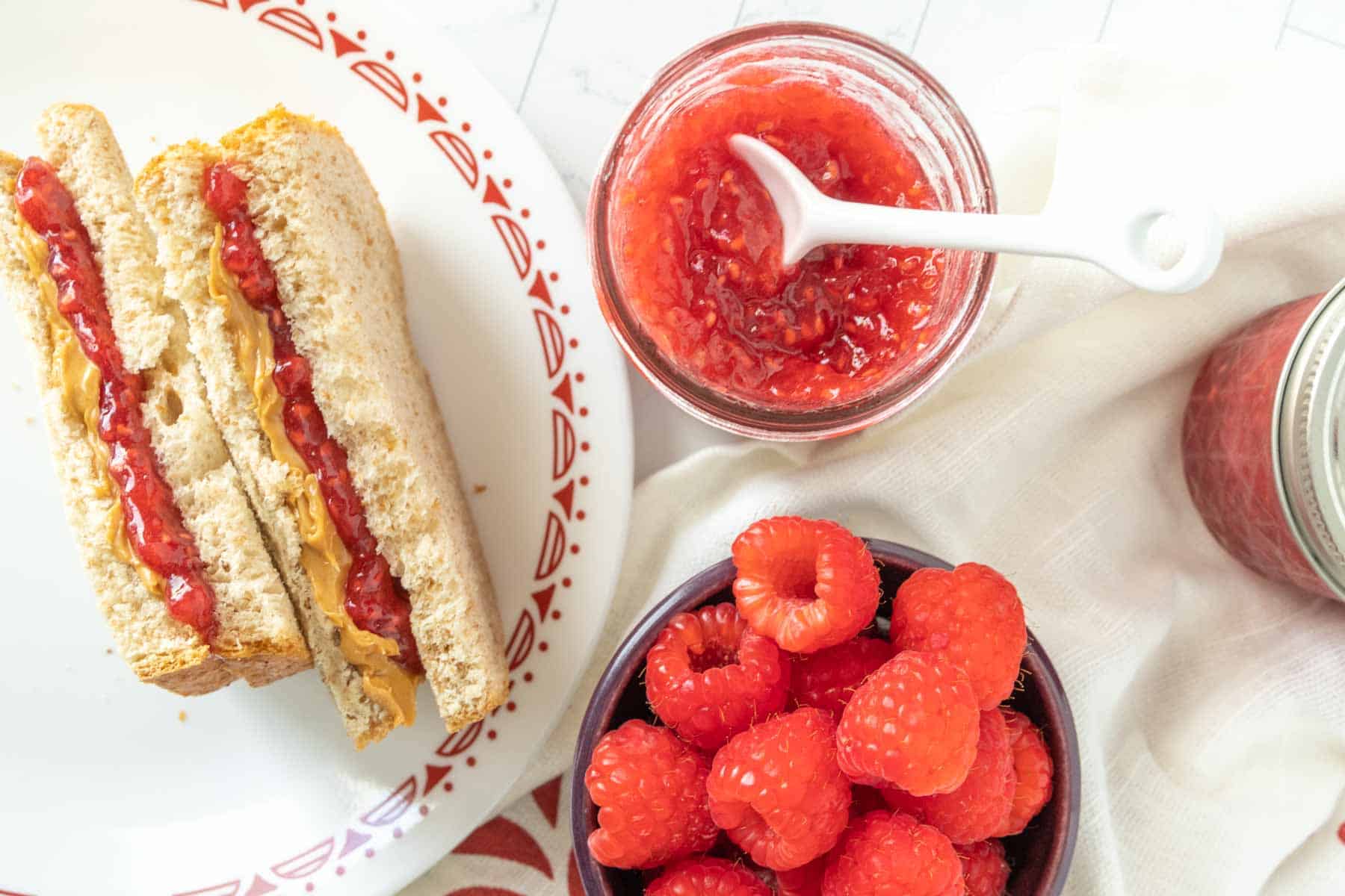 A sandwich with raspberry jam and raspberries on a plate.