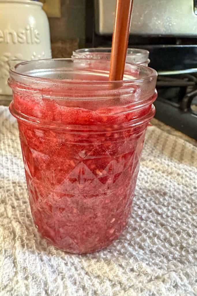 Jars of raspberry jam on a kitchen towel.