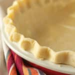 A pie crust in a red and white dish.