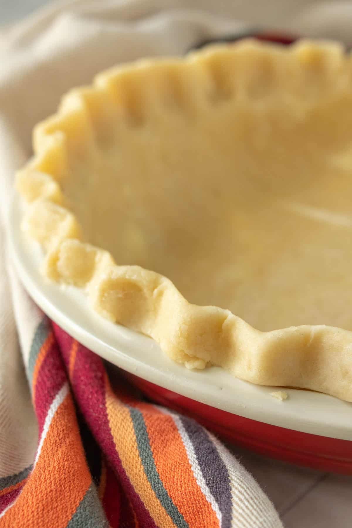 A pie crust in a red and white dish.