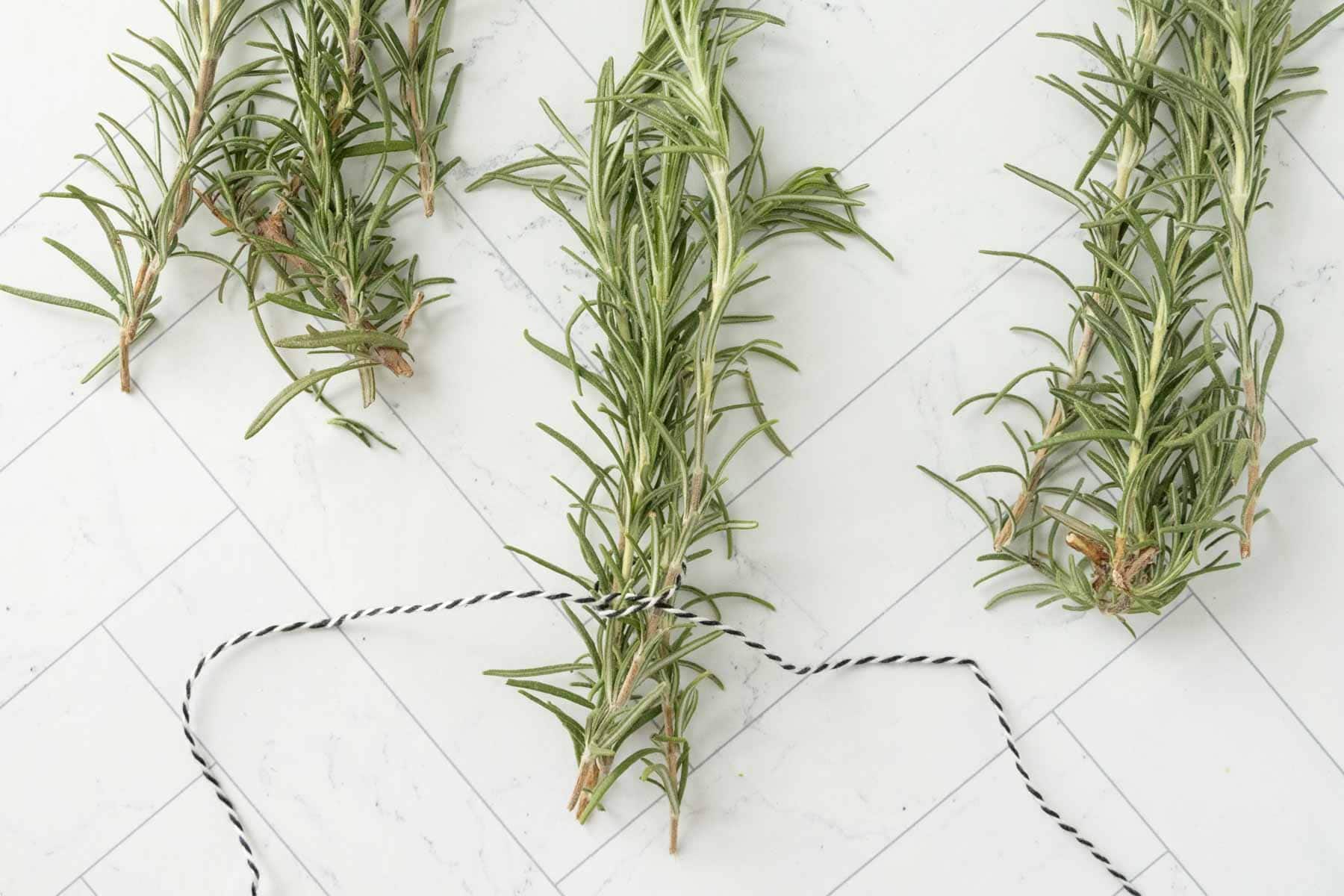 Rosemary sprigs on a white marble countertop.