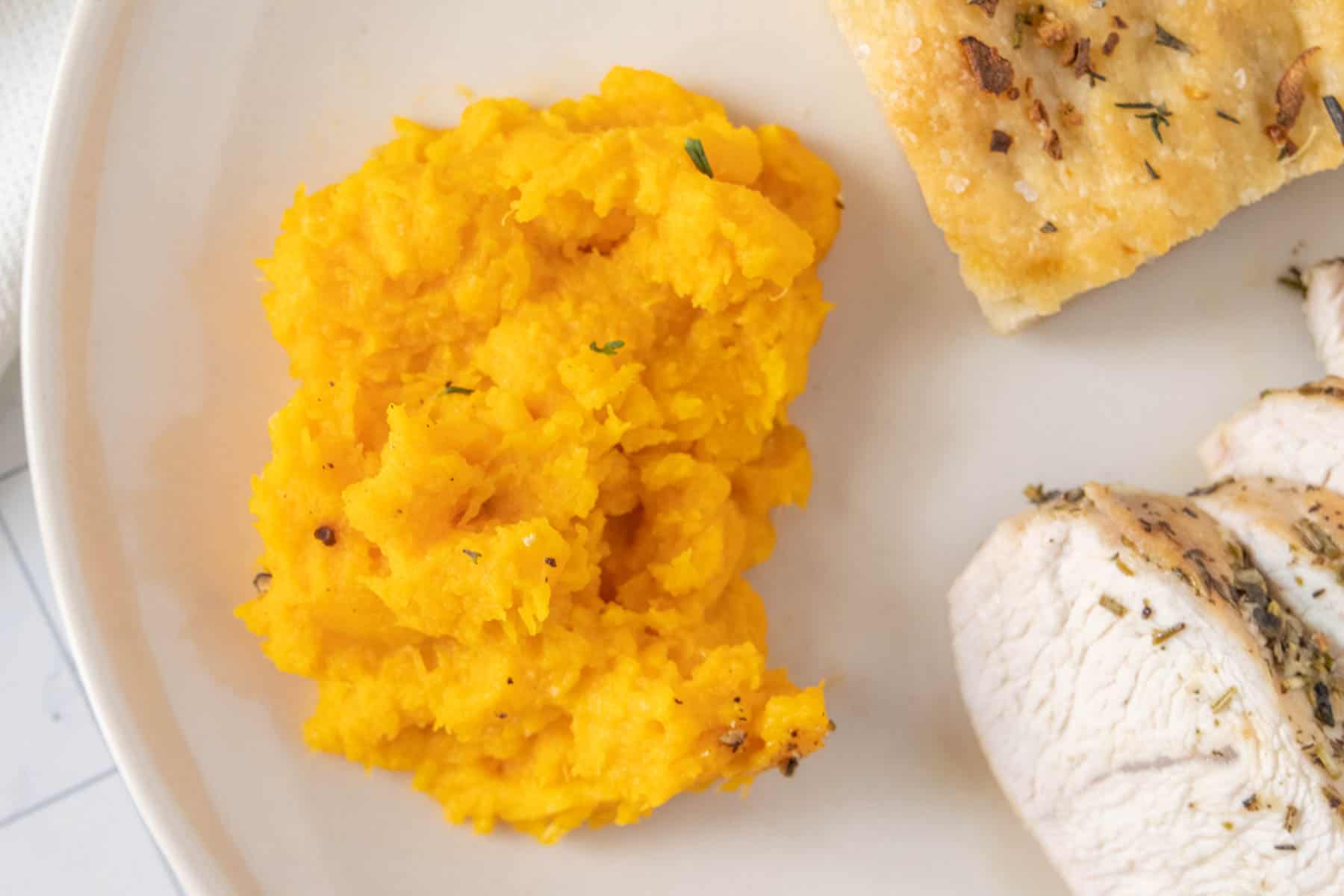 A plate with chicken and mashed butternut squash.