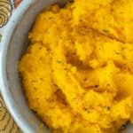 Mashed butternut squash in a bowl on a tablecloth.