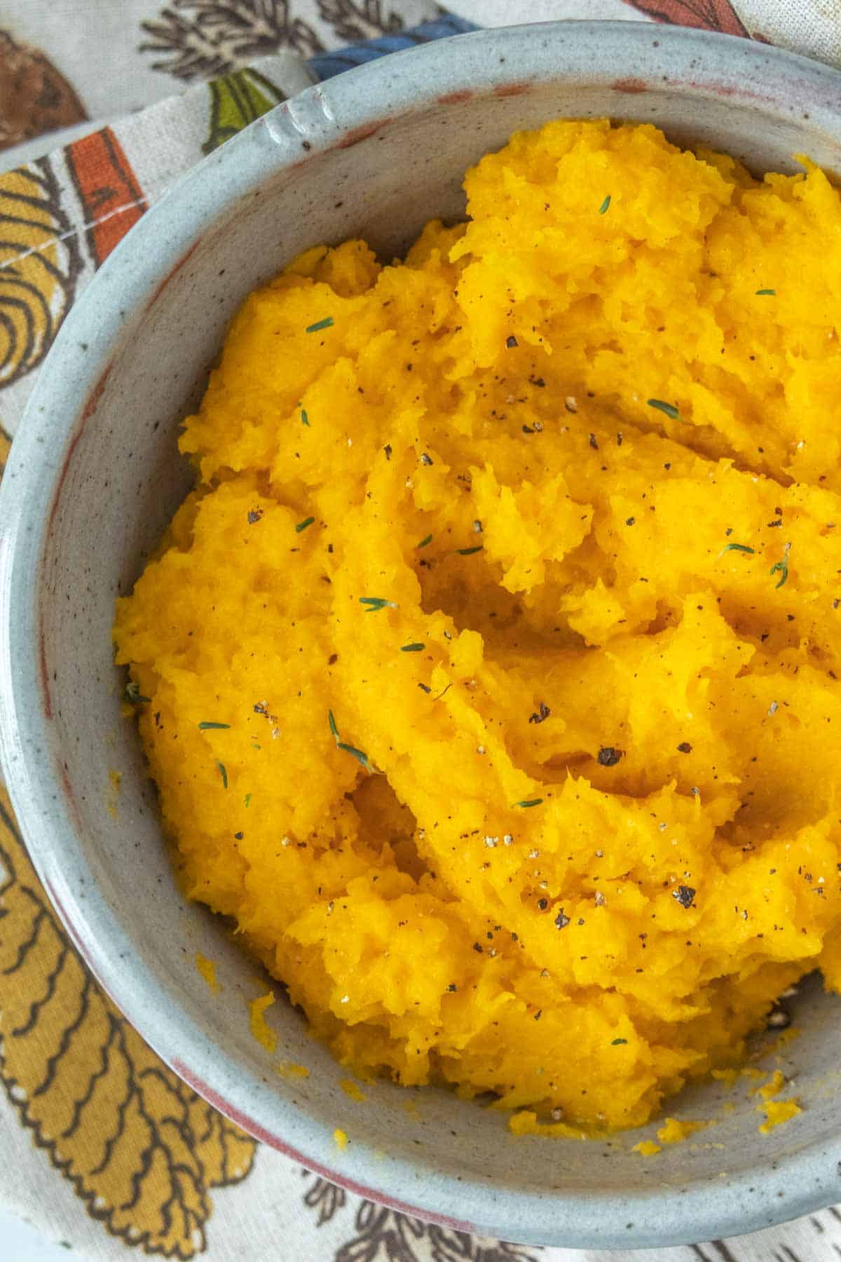 Mashed butternut squash in a bowl on a tablecloth.
