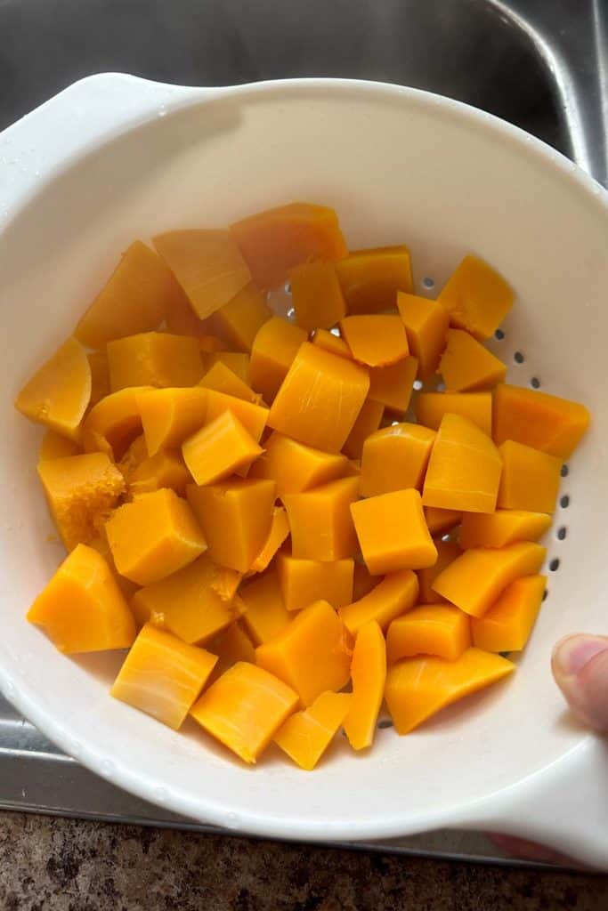 Butternut squash cubes in a colander.