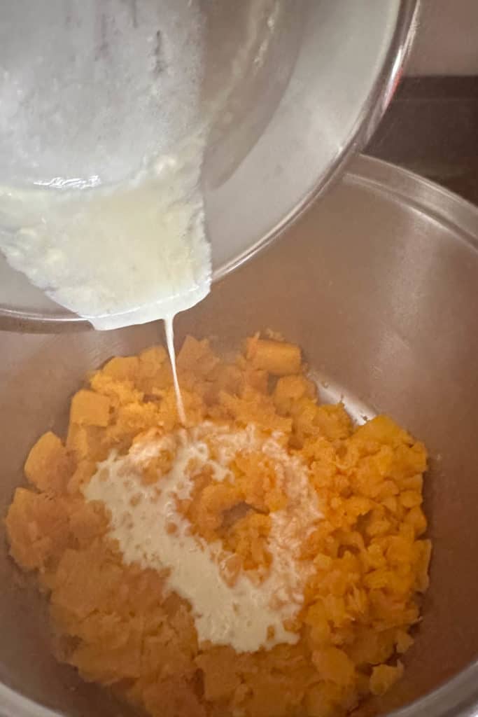 Cream being poured into mashed squash.
