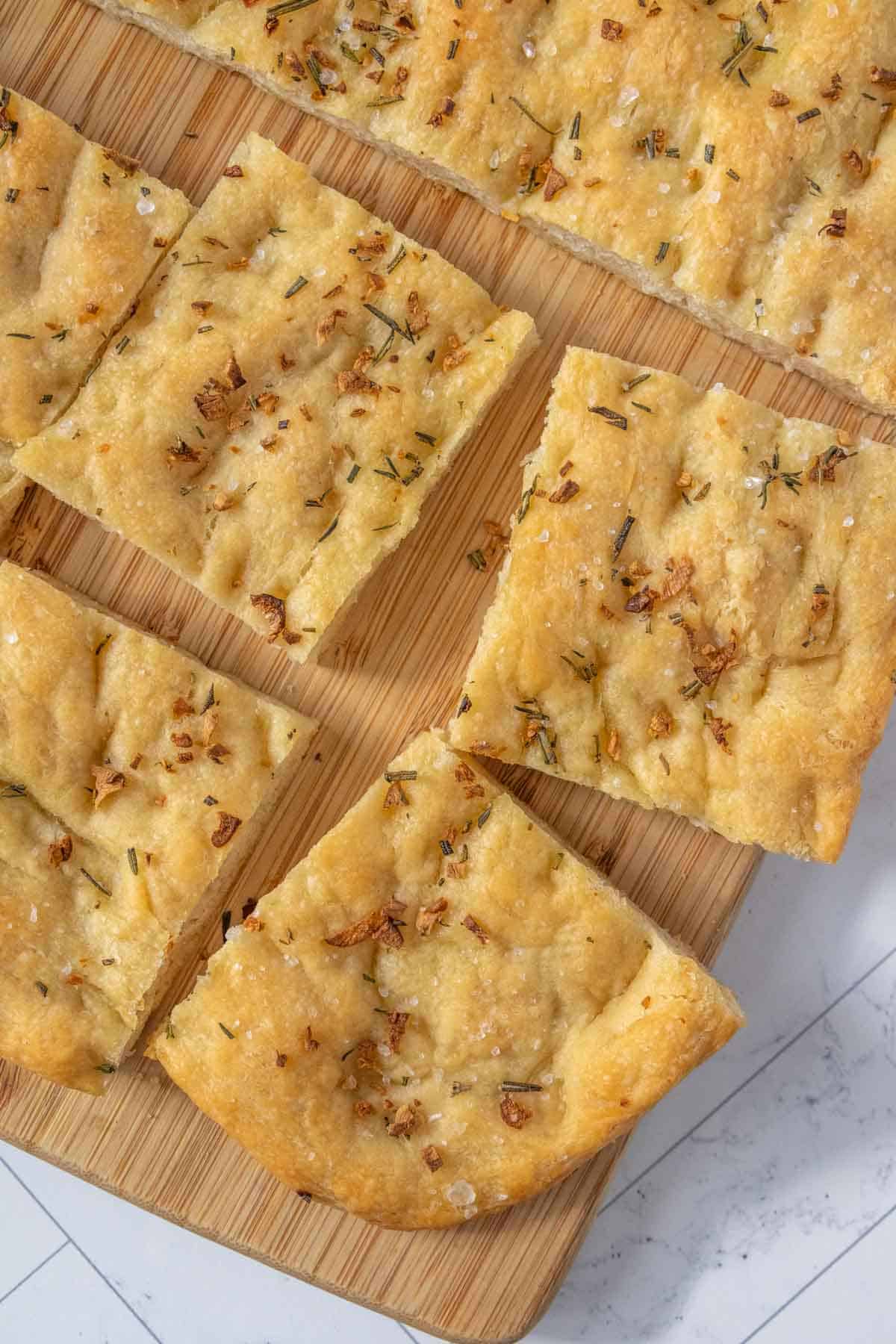 A wooden cutting board with squares of bread on it.