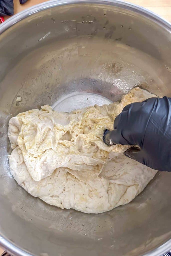 A person is kneading dough in a bowl.