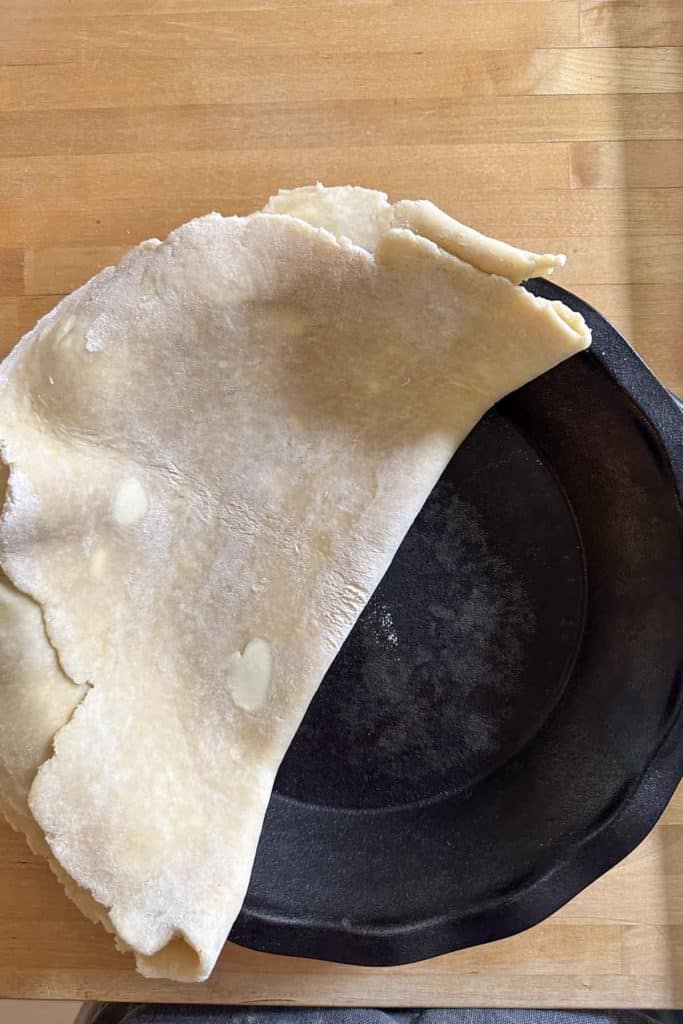 A piece of dough in a skillet on a table.
