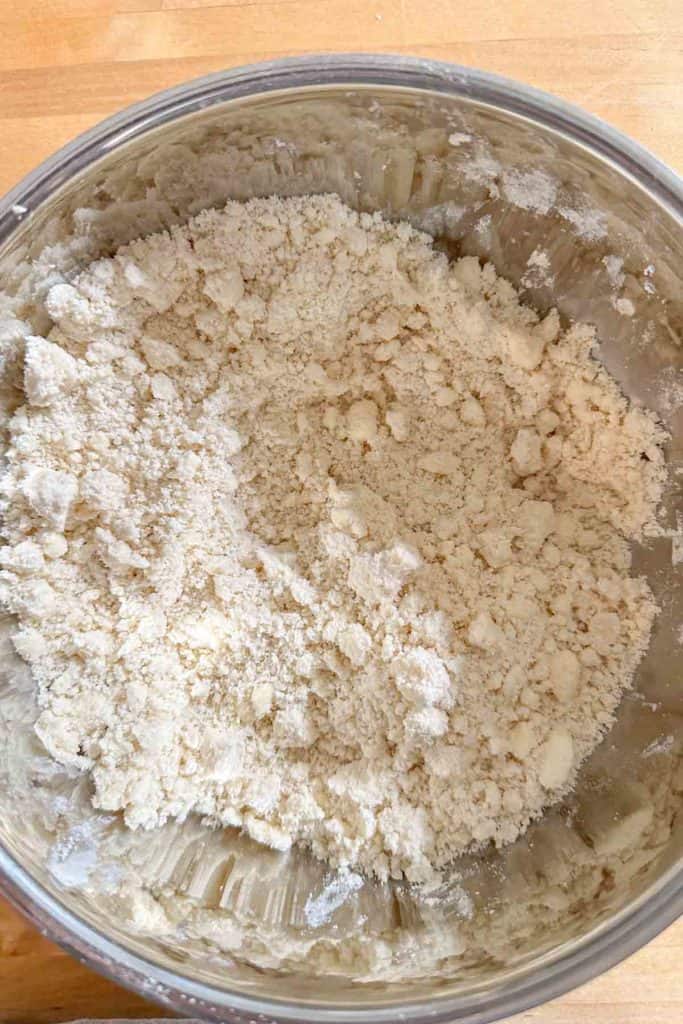 A bowl with flour in it on a wooden table.