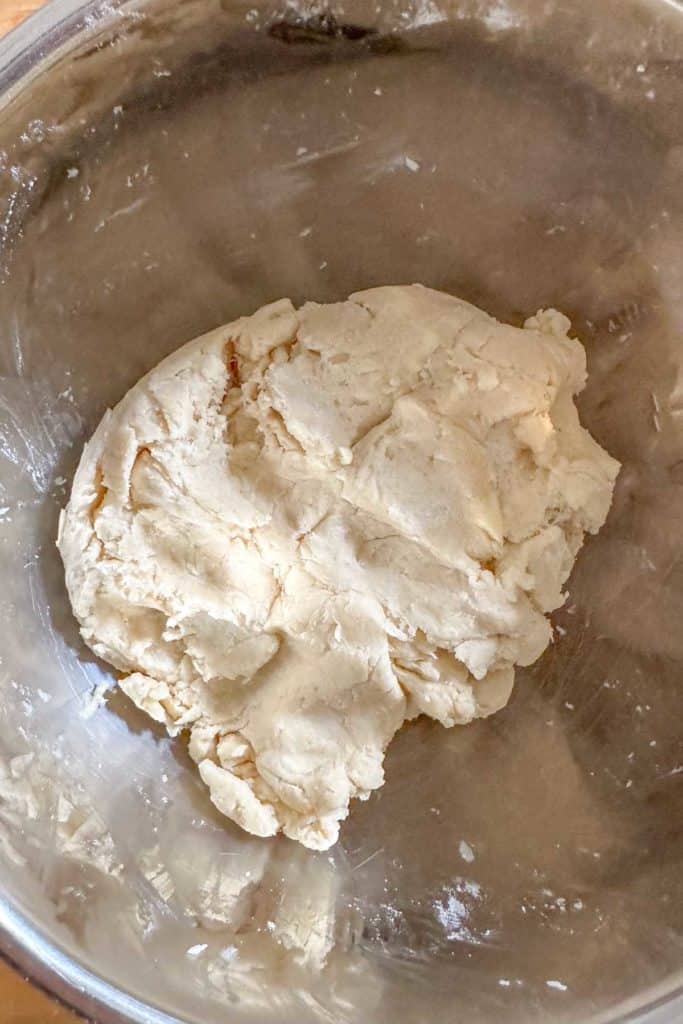 Dough in a bowl on a wooden table.