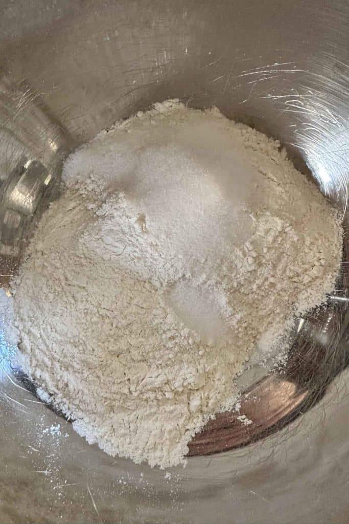 Flour in a metal bowl on a table.