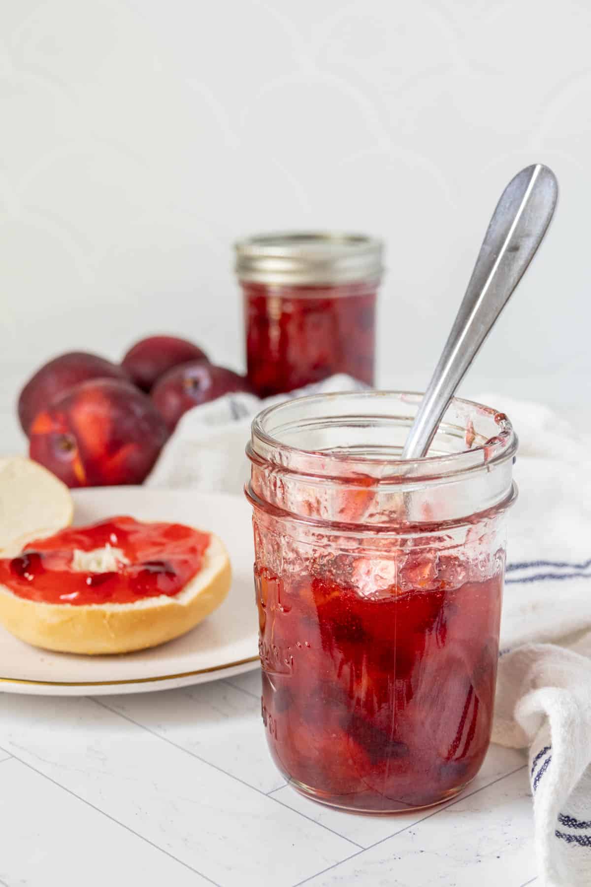 A jar of plum jam with a spoon next to it.