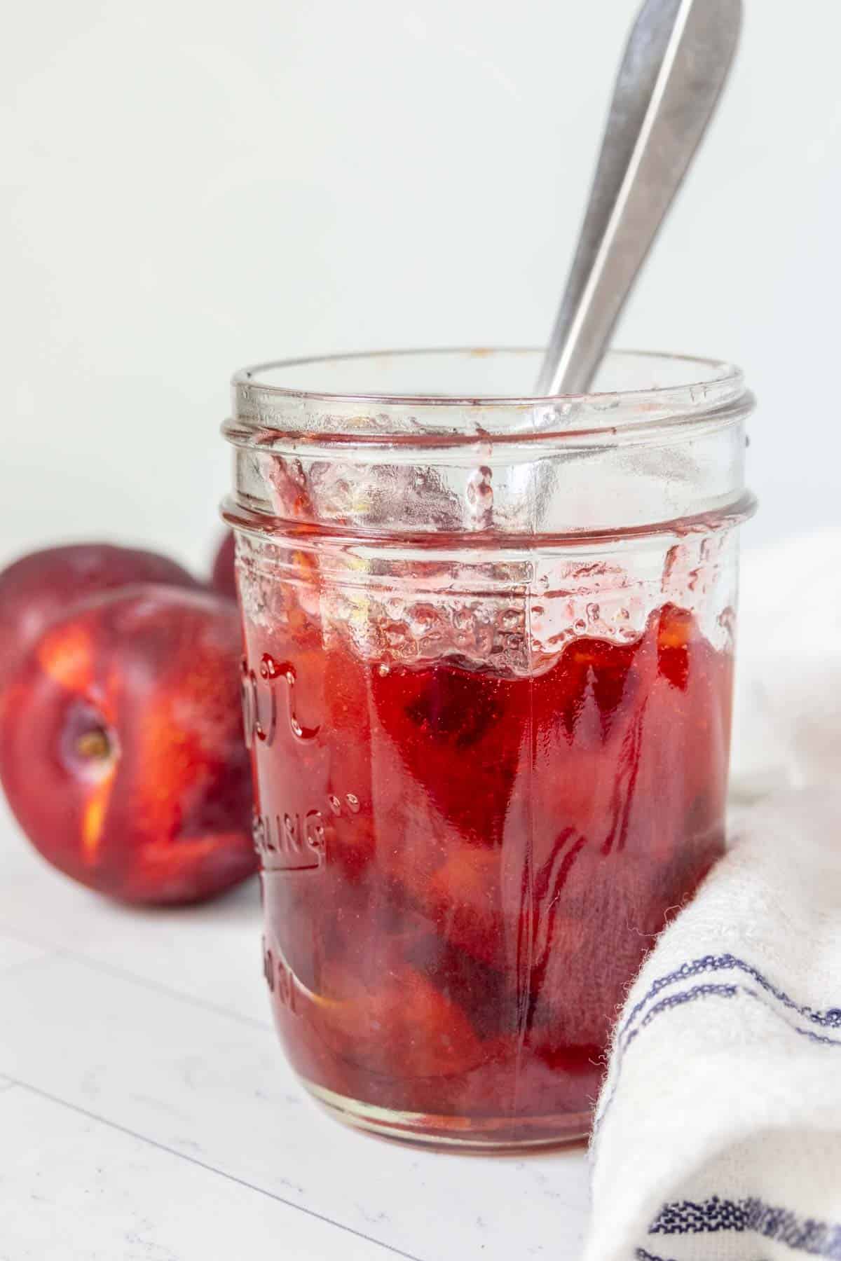 Plum jam in a jar with a spoon.