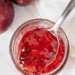Plum jam in a jar with a spoon.