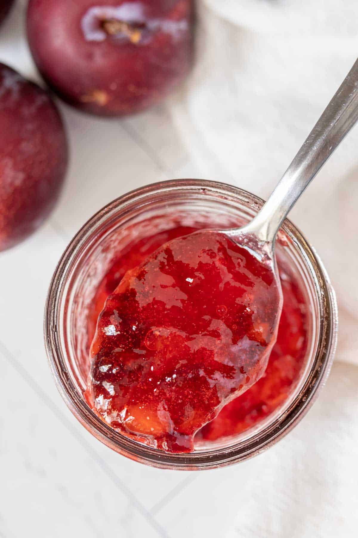 Plum jam in a jar with a spoon.