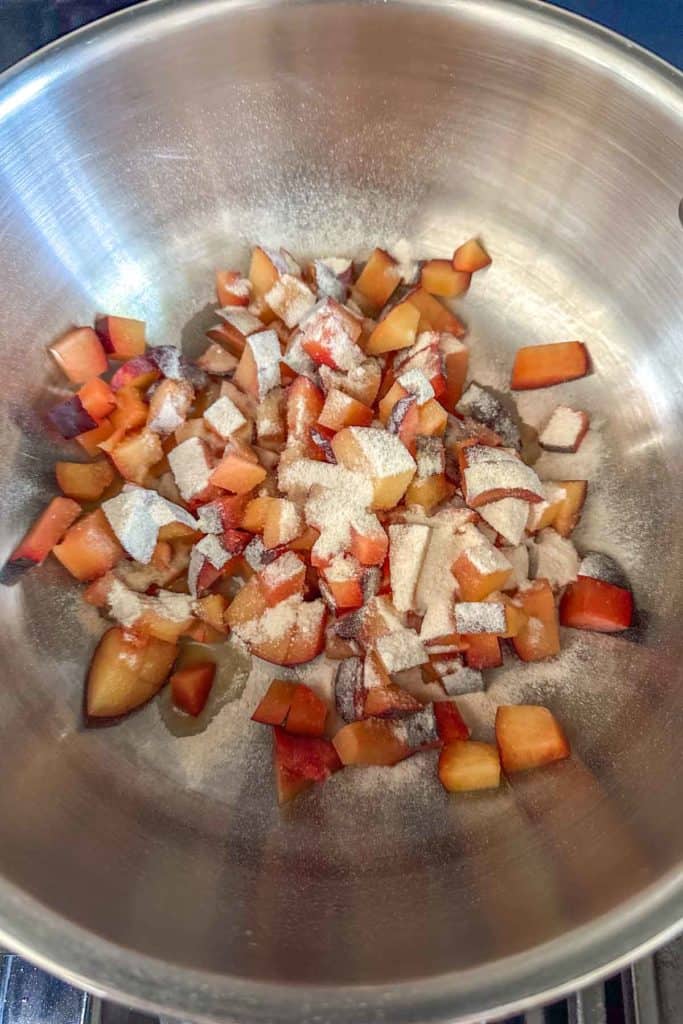 Sliced plums in a pan on the stove.