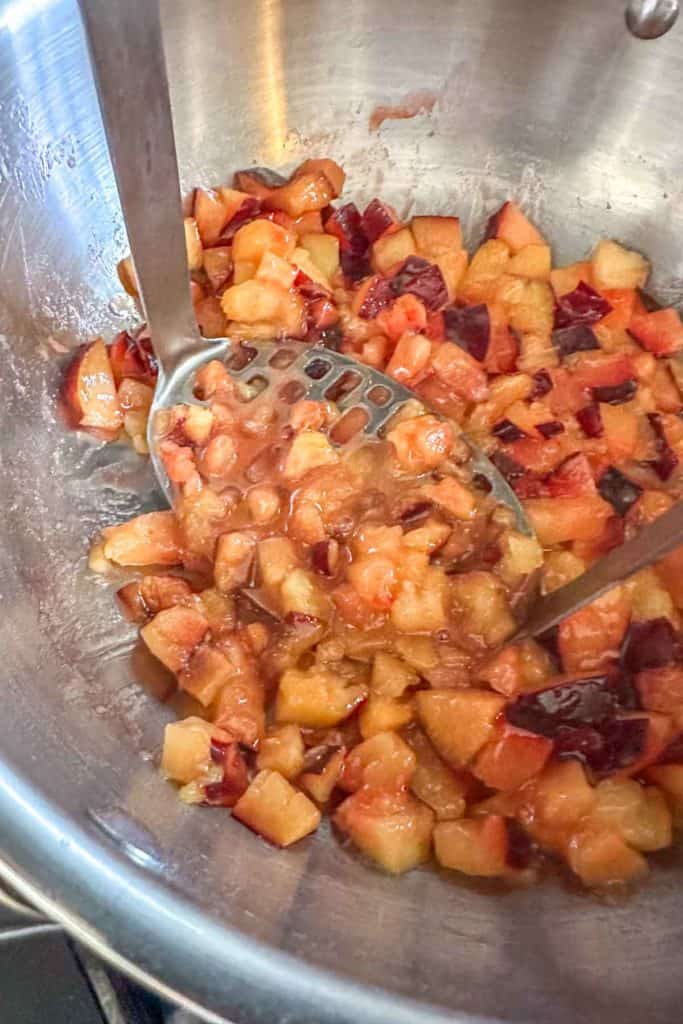 A large bowl of chopped fruit in a pan on a stove.