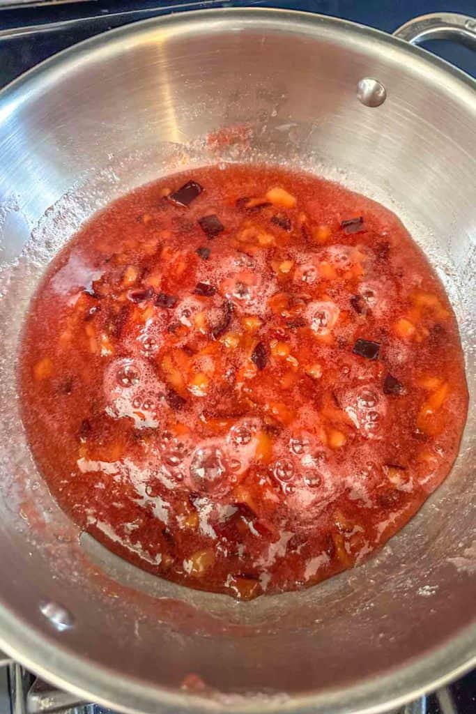 A pan full of red sauce on a stove top.