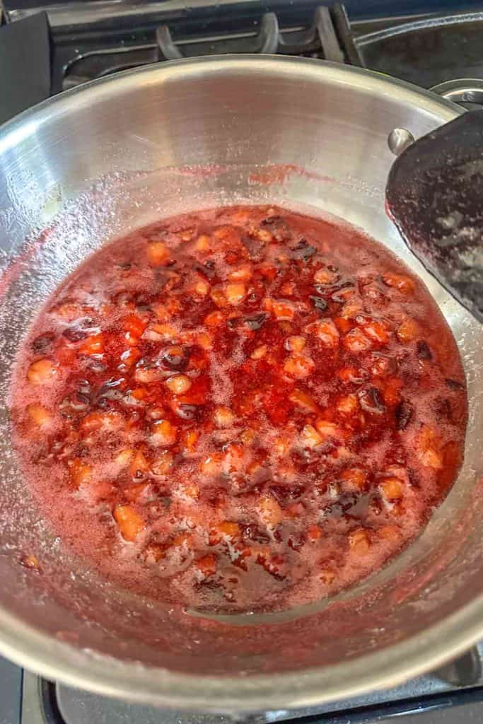 A pan with plums in it on a stove top.