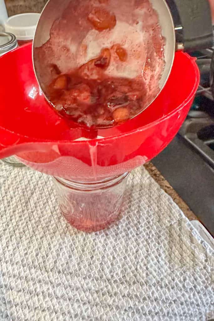 A person pouring something into a red bowl.