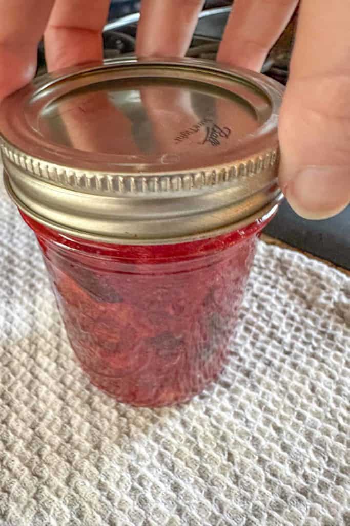 A person holding a jar of plum jam.